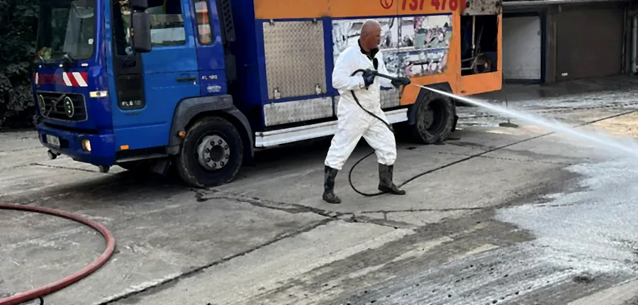 Pracovník firmy KRETSPOL čistí zpevněnou plochu tlakovou vodou z tlakového vozu