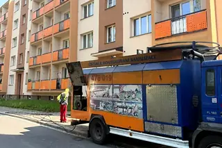 Čištění kanalizace u bytového domu, tlakový vůz a pracovník v reflexní vestě