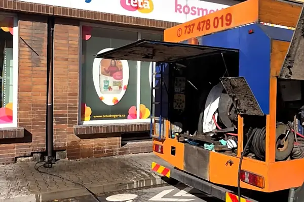 Čištění odtoku před provozovnou, rozvinutá vysokotlaká hadice na chodníku