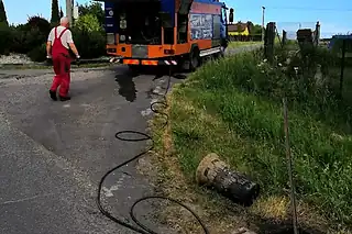 Čištění uliční vpusti tlakovou vodou, hadice vedená od tlakového vozu
